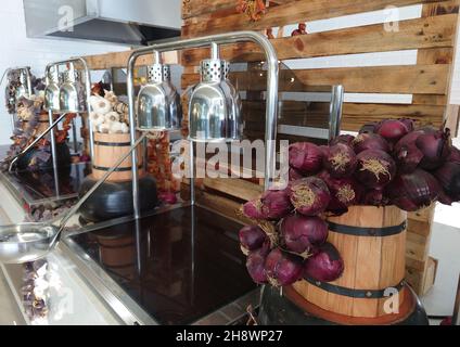 Interior of an upmarket restaurant with buffet counters with heated trays for serving and decor of dried fresh vegetables on wooden barrels Stock Photo