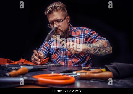 Leather Tanner cuts out leather goods in the work area Stock Photo