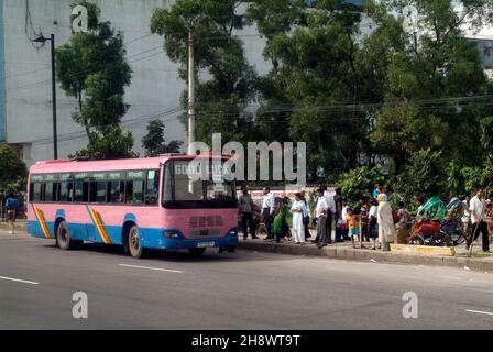 Dhaka, Bangladesh - September 17, 2007: Unidentified people by bus stop on street and others with rickshaws Stock Photo