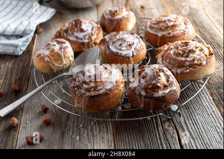 Homemade cinnamon rolls with hazelnut filling on a cooling rack on wooden table Stock Photo