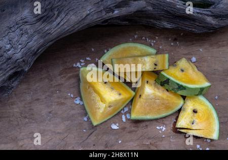 Fresh juicy yellow watermelon cut into triangles on old wooden background. Tropical fruits, Top view, Select focus. Stock Photo