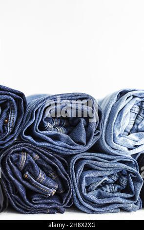 Pile of blue colored folded and crumple denim pants placed in light studio Stock Photo