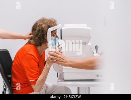 Bearded male with netbook talking on cellphone while sitting on couch and looking away in living room Stock Photo