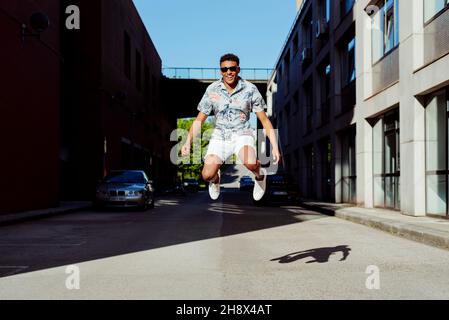 Trendy young black man jumping in the middle of the street Stock Photo