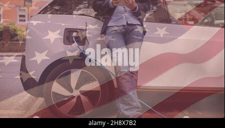 Double exposure of american flag over man using smartphone leaning on charging electric car Stock Photo