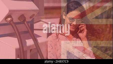 Digital composite of smiling woman talking on phone at electric charging station with union jack Stock Photo