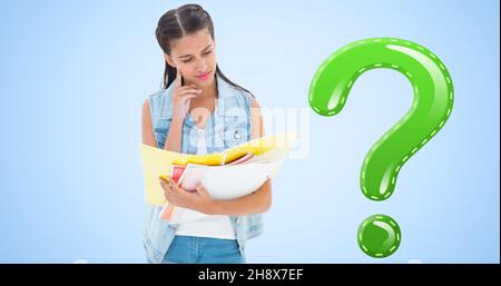 Confused teenage girl reading file by green question mark against blue background Stock Photo