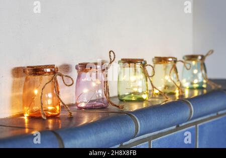 Led lights in colored glasses on tiled stove Stock Photo