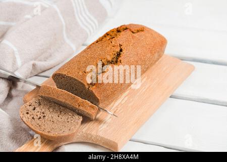 Homemade sourdough rye bread sliced on a cutting board on white table, close-up image, selective focus Stock Photo