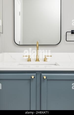 Modern Bathroom with Gray Cabinets Gold Fixtures Black Frame Rectangle Mirror Stock Photo