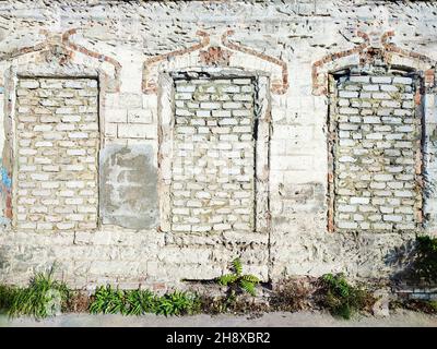 Old white brick wall with three bricked up windows Stock Photo