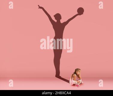 Conceptual image with kid, little girl and shadow of female gymnast on studio pink wall. Dreams about sport career Stock Photo