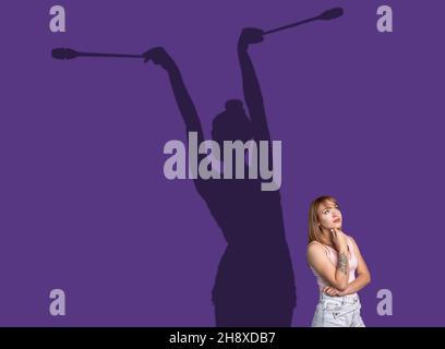 Conceptual image with young girl and shadow of female gymnast on studio purple wall. Dreams about sport career Stock Photo