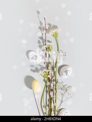 Easter composition suitable for greeting card. Flower spring flat lay with white flowers, willow twigs and decorative eggs on a blue background with b Stock Photo