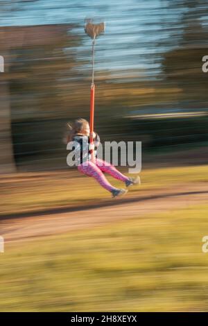 RAJHRAD, CZECH REPUBLIC - Oct 22, 2021: A long exposure of a little girl having fun on the swing Stock Photo