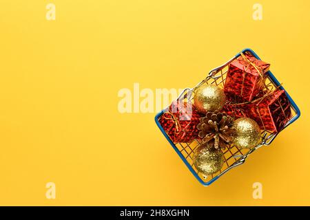 Christmas gifts and toys in a basket on a bright yellow background, empty space for text on the left. New year and Christmas background. Stock Photo