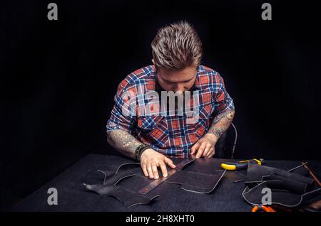 Portrait of leather craftsman working making measupenets in patterns at table in workshop studio Stock Photo