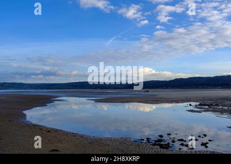 Reflections of vapour trails and clouds in the estuary at Red Warf Bay, Anglesey, North Wales, UK Stock Photo