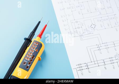 Yellow voltage indicator with an electrical diagram on a blue background. Testing and verification of power grids Stock Photo