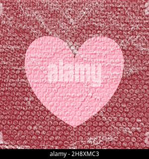 Heart symbol with bubble wrap and copy space against a red background Stock Photo