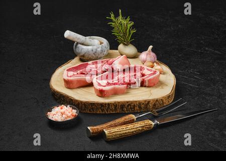 Raw fresh lamb double loin chop with meat fork, herb and spices Stock Photo