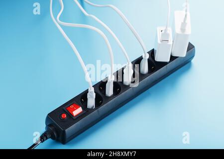 Surge protector with connected white wires of electrical appliances on a blue background. Free space Stock Photo