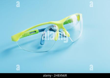 Technological protective green glasses isolated on a blue background. Reliable eye protection, free space Stock Photo