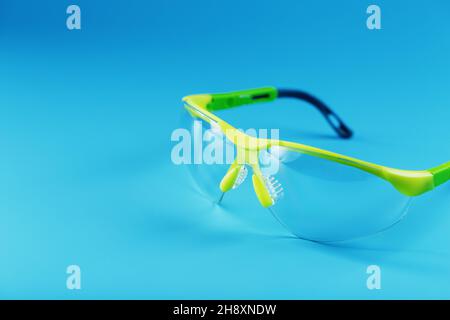 Technological protective green glasses isolated on a blue background. Reliable eye protection, free space Stock Photo