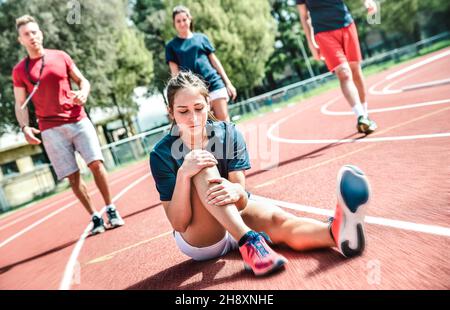 Female sportler getting injured at athletic workout training - Male coach taking care on sport pupil after physical accident - Team care concept Stock Photo