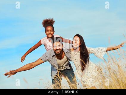 child daughter family happy mother father piggyback fun together girl cheerful field outdoor natur summer Stock Photo