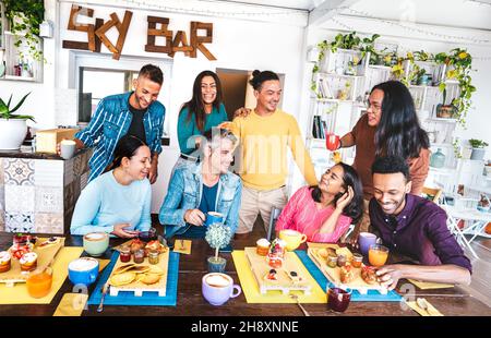 Friends having fun at breakfast buffet - Trendy multicultural people eating morning brunch at sky bar cafeteria - Life style concept Stock Photo