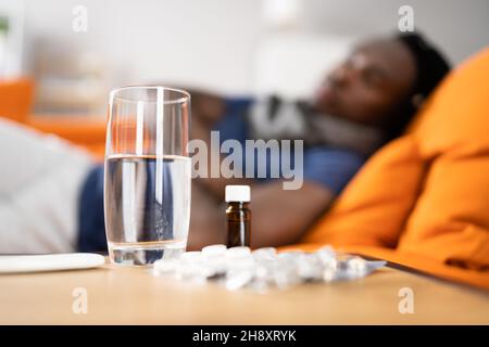 Sick African American Man On Sofa. Fever Concept Stock Photo