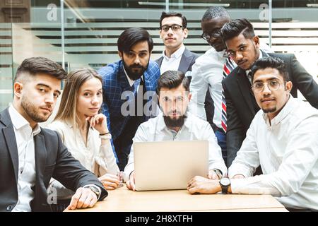 A team of young office workers, businessmen with laptop working at the table, communicating together in an office. Corporate businessteam and manager Stock Photo
