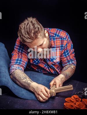 Leather Skinner creating new leatherwork at the tanning shop Stock Photo