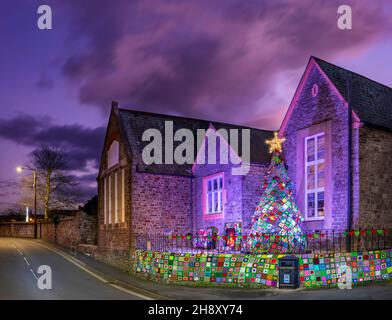 Appledore, North Devon, UK. 2nd Dec, 2021. A giant knitted and crocheted 'Christmas Eve Fireside Scene' lights up the evening in Appledore, North Devon. Volunteers spent many hours crocheting enough squares to produce the amazing display which includes a chair, Christmas stockings, sleeping cat, pom-pom robins, mistletoe and the giant 4.5 metre tree. Credit: Terry Mathews/Alamy Live News Stock Photo