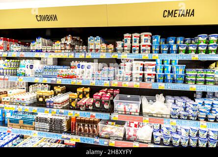 Novgorod, Russia - August 30, 2021: Various fresh dairy products ready for sale in chain superstore. Text in Russian: cream, sour cream Stock Photo