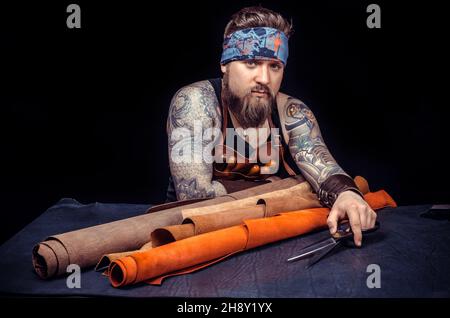 Craftsman demonstrates leather cutting process at the shop Stock Photo