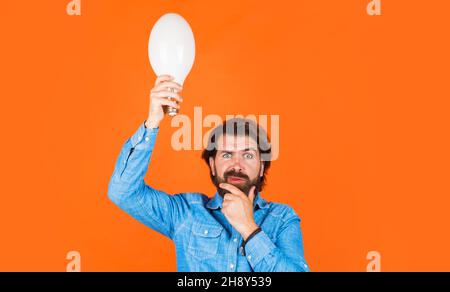Good idea. Thinking man with light bulb. Innovation and inspiration. Bearded male with Lamp in hand. Stock Photo