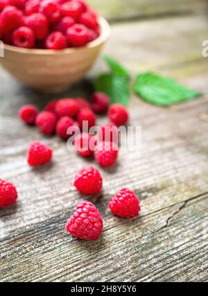 Fresh ripe red raspberries with leaves in a bowl on rustic old wooden table. Healthy organic food, summer vitamins, BIO viands, natural background. Co Stock Photo