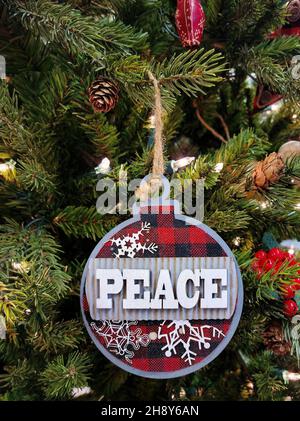 Close up of Christmas peace ornament on a pine tree with holiday lights Stock Photo