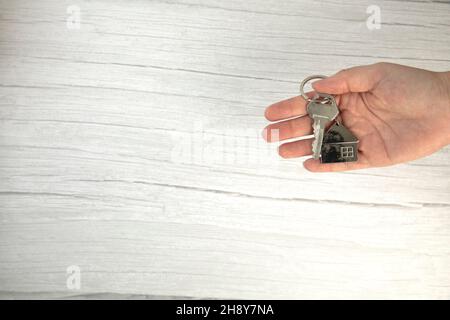 realtor female hand holding new door key to new house on white background top view with copy space, buying new home concept Stock Photo