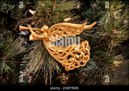 Gold Christmas ornament of archangel or angel Gabriel blowing horn, hanging from a fir tree. Gabriel means '˜God is my Strength' or 'Strength of God'. Stock Photo