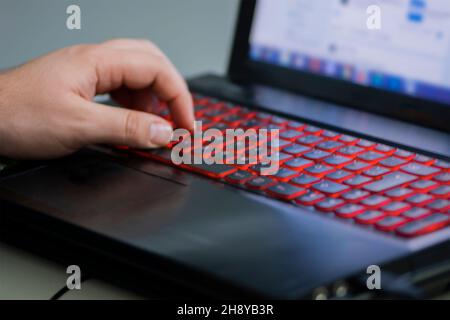 Man's left hand on the illuminated laptop keyboard Stock Photo