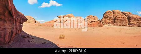 Rocky massifs on red sand desert, bright blue sky in background - typical scenery in Wadi Rum, Jordan Stock Photo