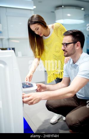 Young couple choosing equipment for their home. Buying washing machine. Stock Photo