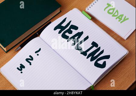 Sign displaying Healing. Word for process of making or becoming sound or healthy again Helping injured Plain Blank Open Notebooks With Stack Of Pens Stock Photo