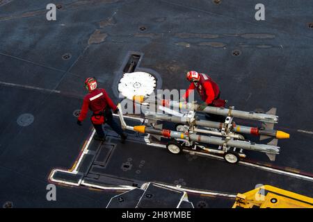 211202-N-PV401-1140 PHILIPPINE SEA (Dec. 2, 2021) Sailors move ordnance on the flight deck of Nimitz-class aircraft carrier USS Carl Vinson (CVN 70), Dec. 2, 2021. Carl Vinson Carrier Strike Group is on a scheduled deployment in the U.S. 7th Fleet area of operations to enhance interoperability through alliances and partnerships while serving as a ready-response force in support of a free and open Indo-Pacific region. (U.S. Navy photo by Mass Communication Specialist Seaman Elizabeth Grubbs) Stock Photo