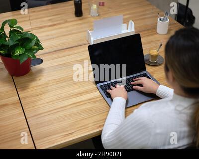 view from behind of a woman using her laptop in a coworking space Stock Photo