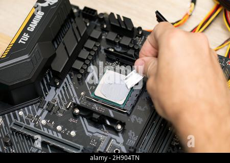 Man apply thermal paste for installing microprocessor on Tuf Gaming b450 plus motherboard. Maintenance computer cpu hardware. Russia, 17.08.2021 Stock Photo