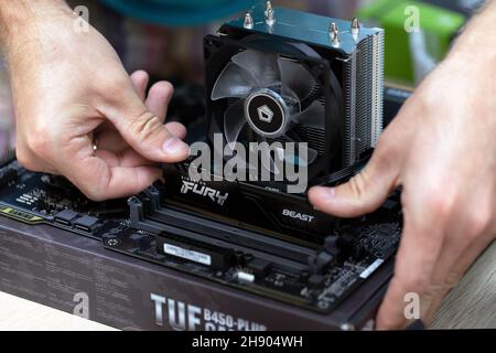 Close up of electronic engineer installing Fury Beast RAM DDR4 stick on motherboard of professional computer for cryptocurrency mining. Russia, 17.08. Stock Photo